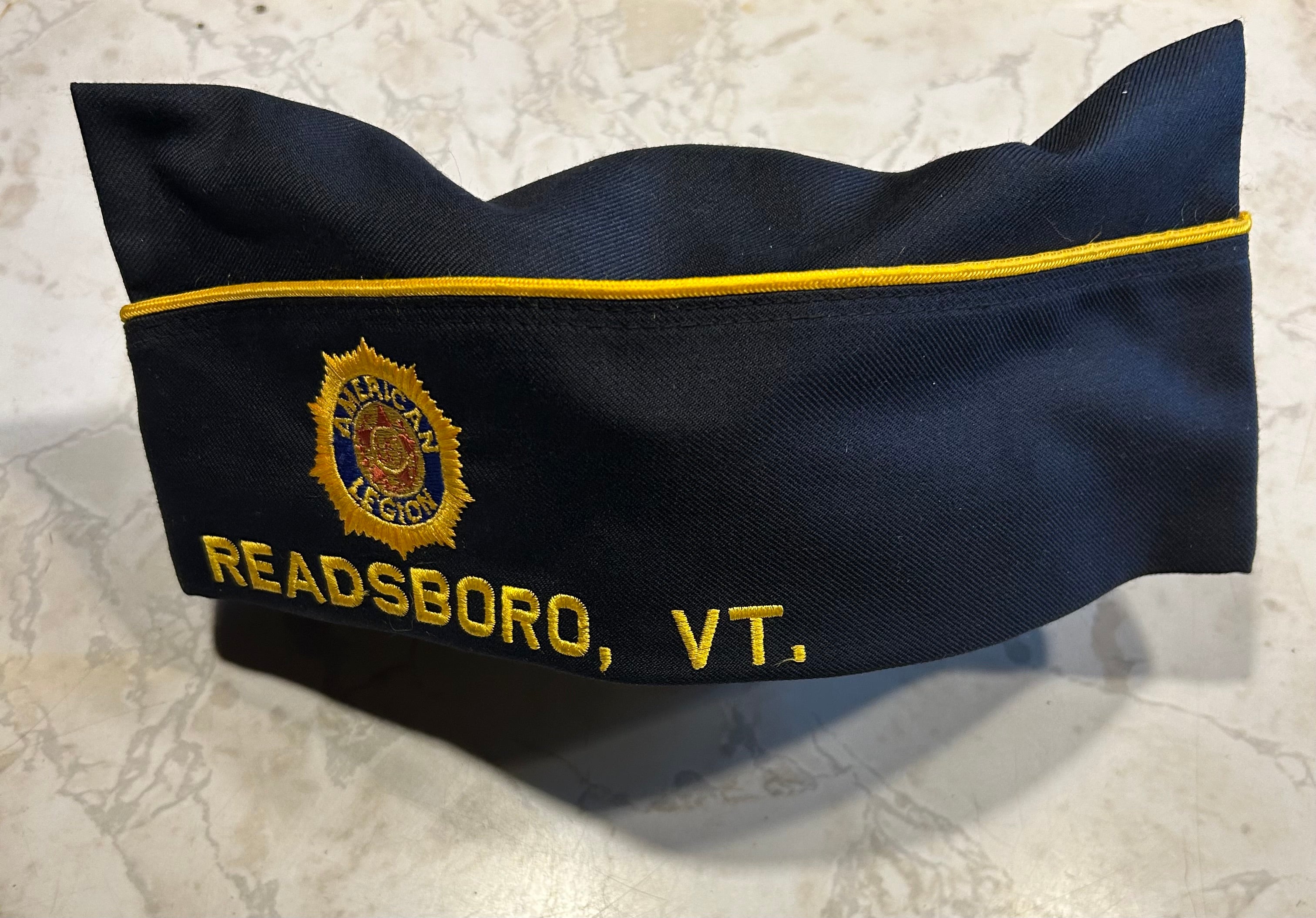 This is a blue American Legion veteran overseas cap adorned with various commemorative pins.