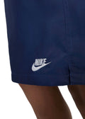 These are navy blue Nike Sportswear Style Essentials woven shorts featuring a standard fit and above-knee length.