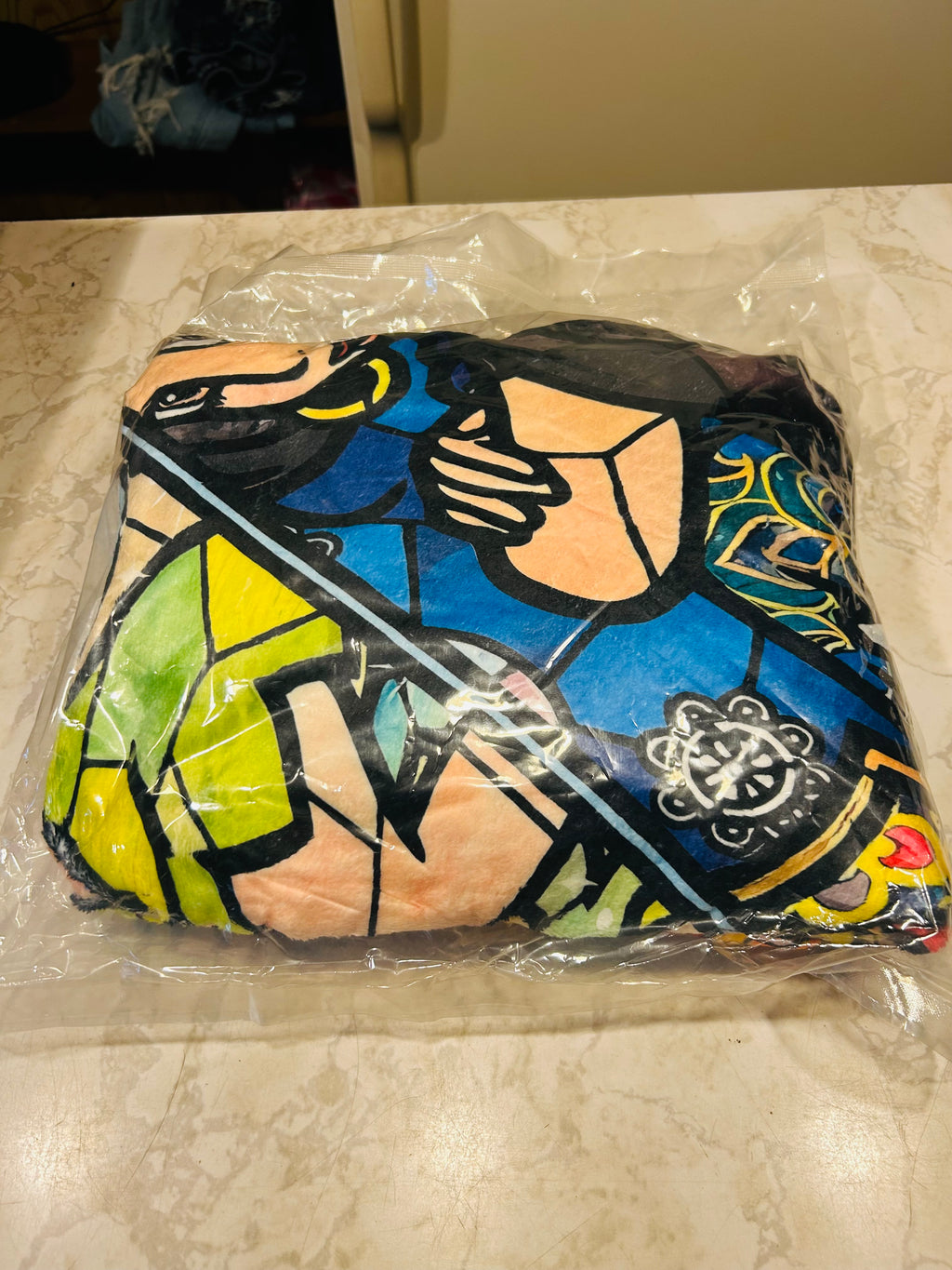 This is a packaged plush throw blanket featuring a colorful, stained-glass inspired graphic artwork.