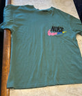This green Nike Sportswear t-shirt features a colorful "Just Do It" graphic on the chest pocket.
