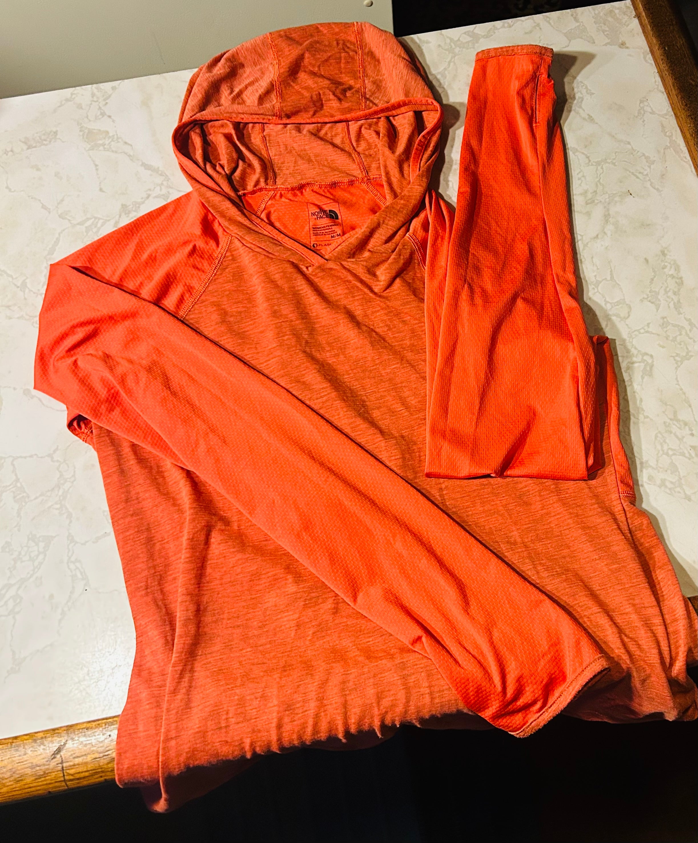 This is a new vibrant orange The North Face FlashDry women's hoodie in size Medium.