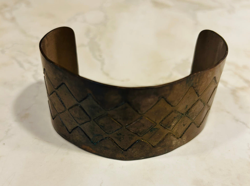 This is a vintage copper cuff bracelet featuring a textured diamond-shaped basketweave pattern.
