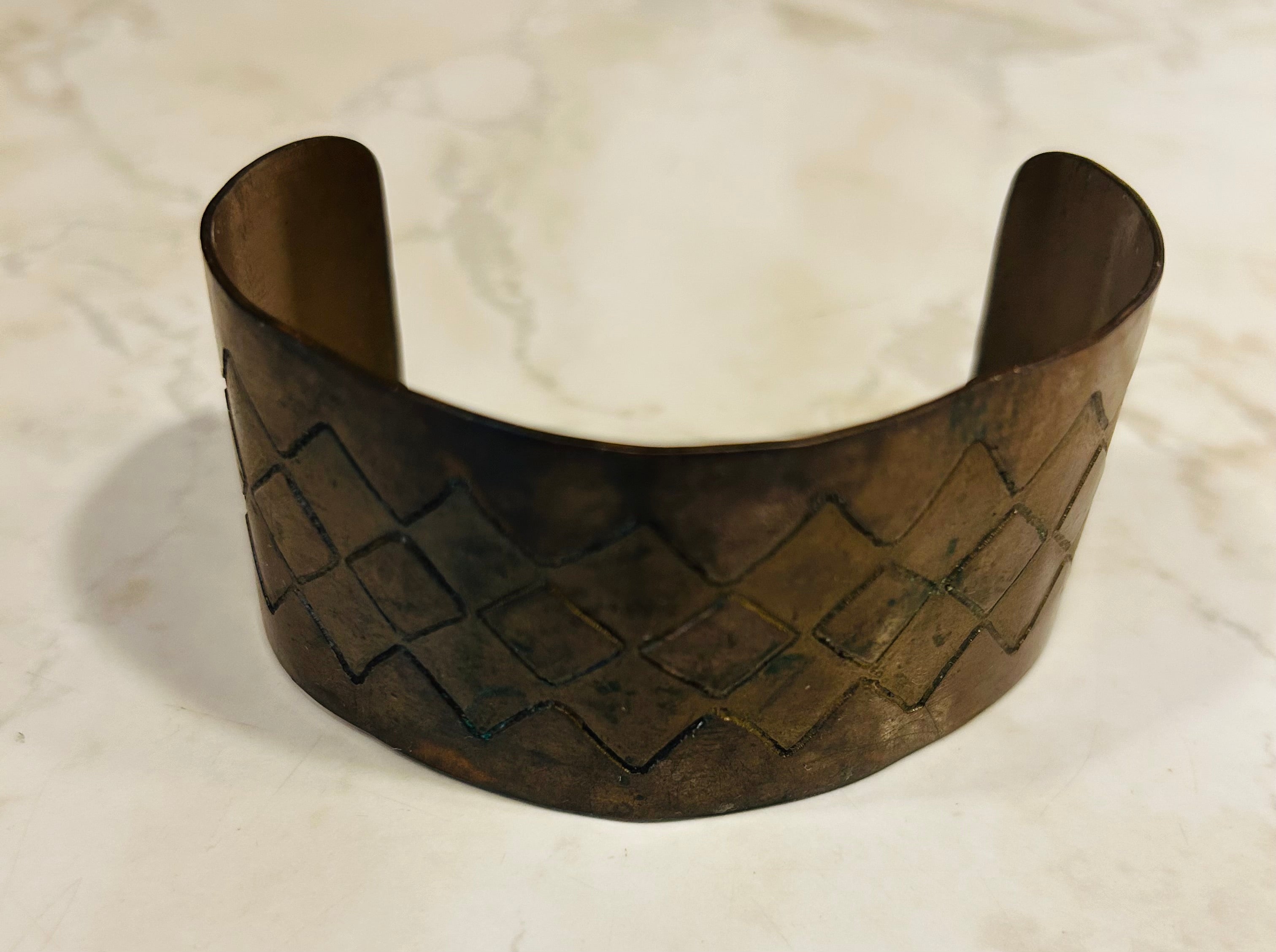 This is a vintage copper cuff bracelet featuring a textured diamond-shaped basketweave pattern.