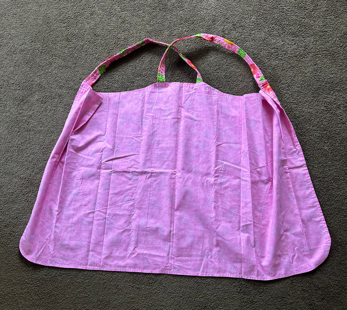 This floral patterned apron features two front pockets and a pink base color.