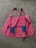 The item in the image is a cross-back kitchen apron (often referred to as a Japanese-style pinafore apron). It features a red patterned design with shoulder straps that cross over the back, along with a solid blue front utility pocket.