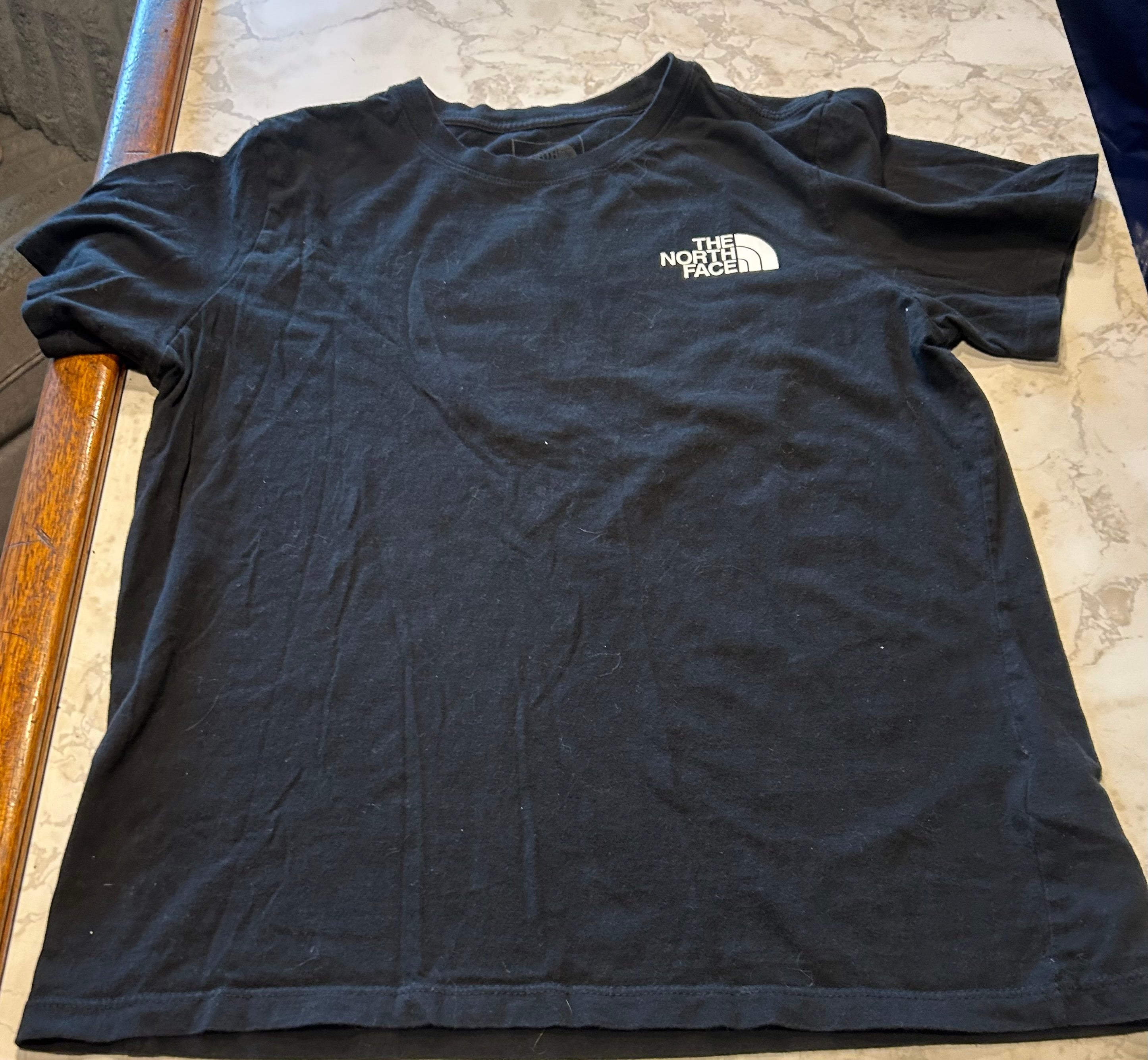 This black is medium North Face "Never Stop Exploring" crew neck t-shirt features a large graphic logo box on the back.